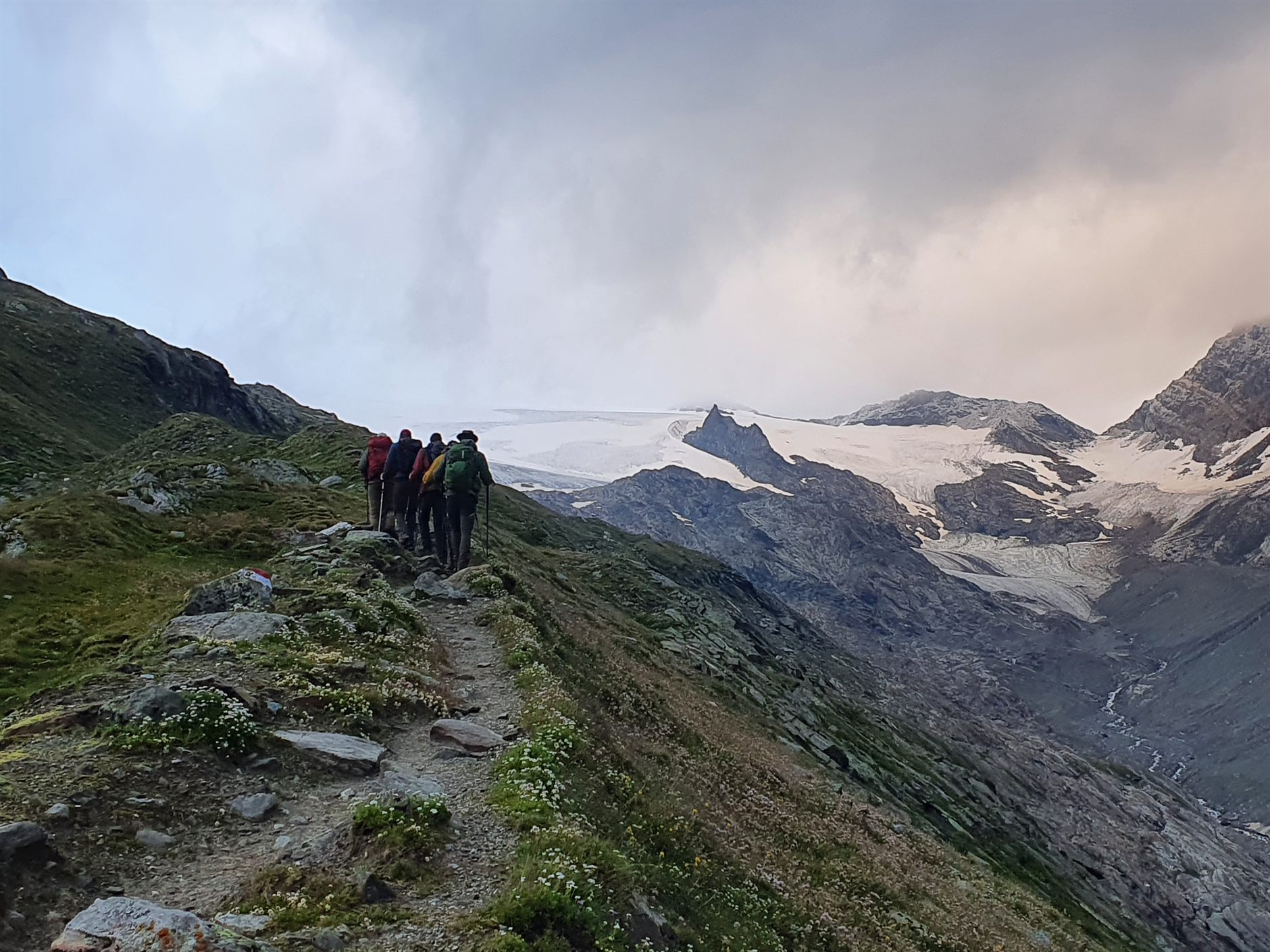 Een groep wandelaars op een bergpad richting een gletsjer